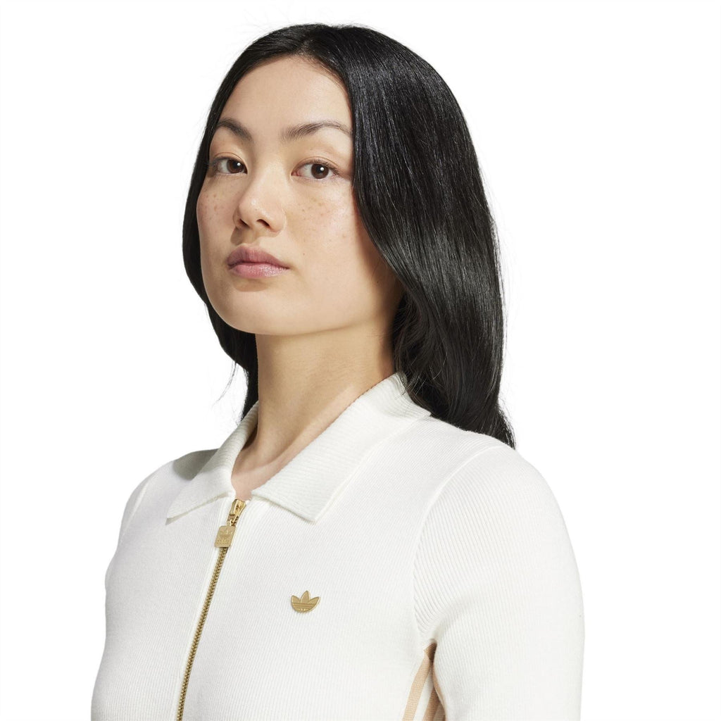 Off-white knit onesie close-up with quarter zip, ribbed knit texture, small chest logo