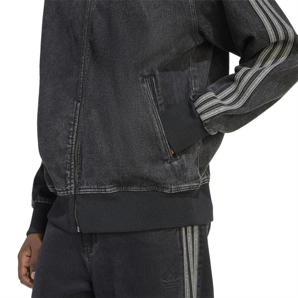 Black denim jacket detail with zip front, ribbed hem, and striped sleeve cuff