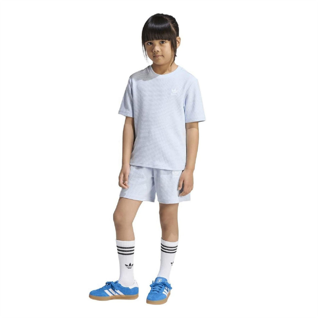 Kids light blue loose T-shirt and shorts set worn by a model, with striped socks.