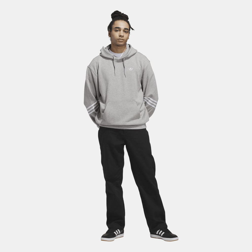 Grey adidas Originals pullover hoodie on model with drawstring hood and sleeve stripe detail.
