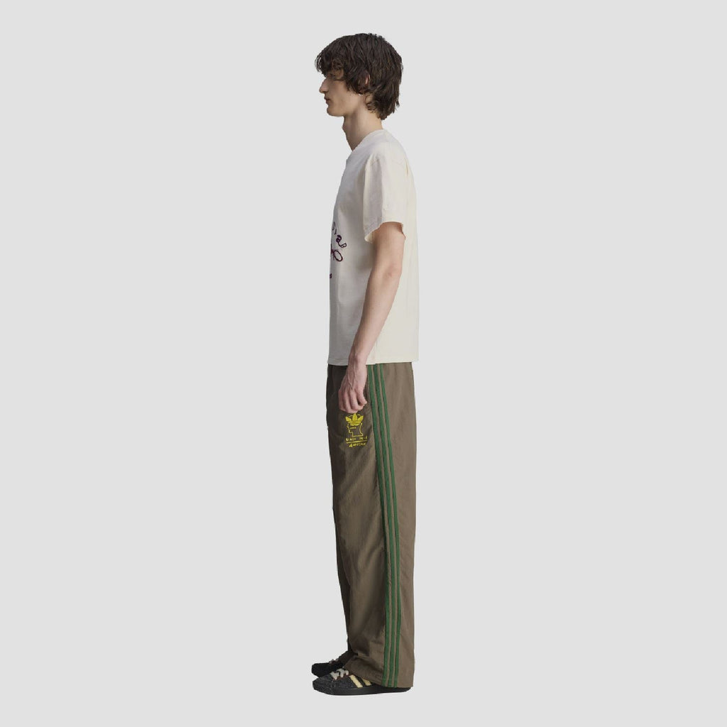 Chocolate track pants with green side stripes and yellow logo patch, straight wide leg
