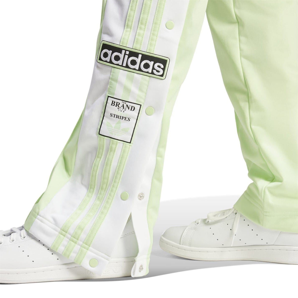 Light green track pants with white vertical stripes and adidas brand patch