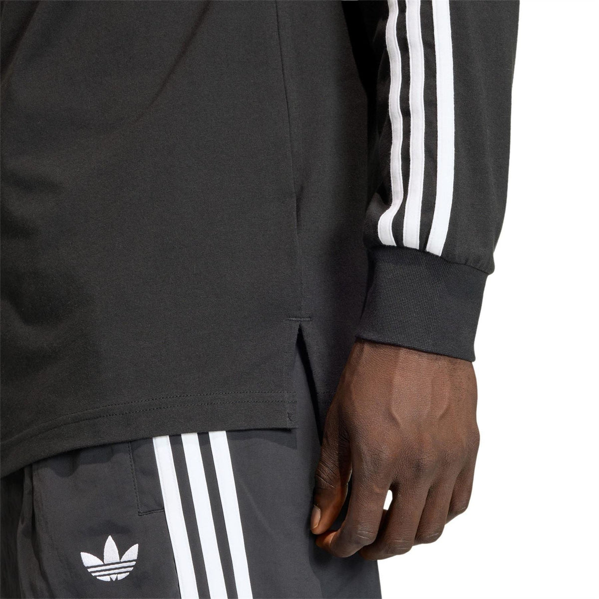 Black long-sleeve shirt detail with white side stripes and adidas trefoil logo