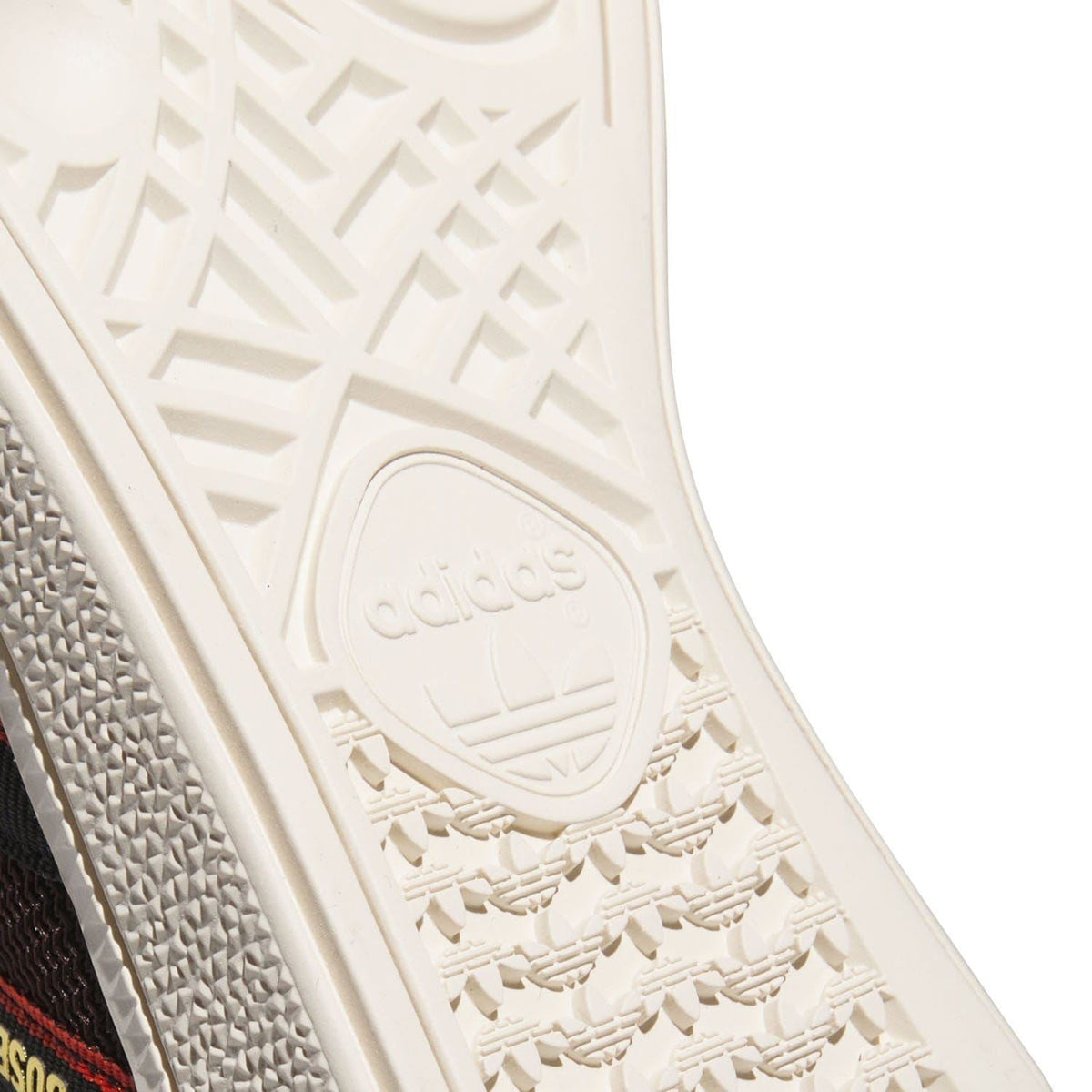 Close-up of white outsole tread with adidas oval logo and textured traction pattern