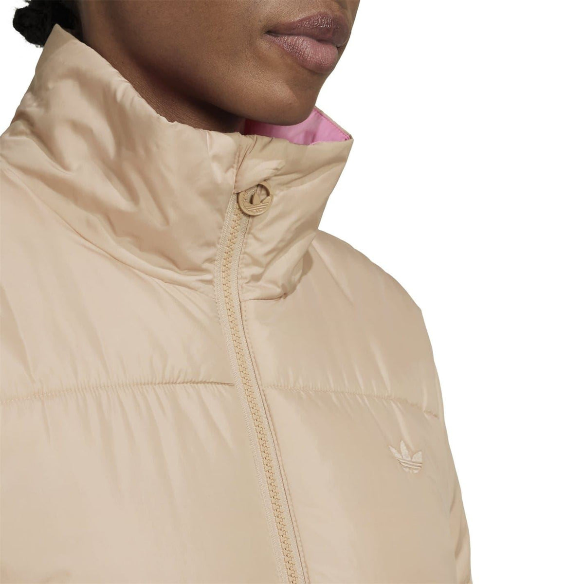 Beige high-neck jacket close-up with zipper placket and adidas Originals trefoil logo.