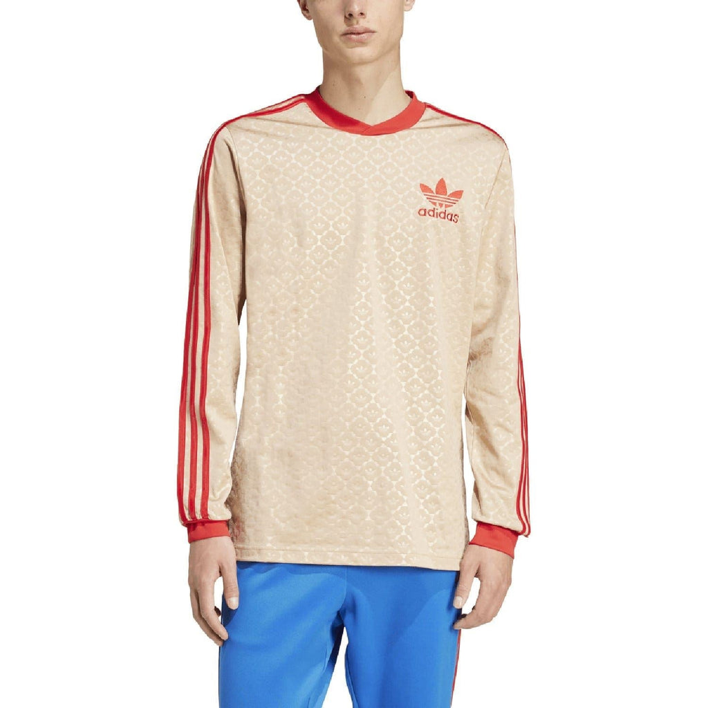 Beige adidas Originals jersey with red-trim stripes down sleeves, worn with blue pants