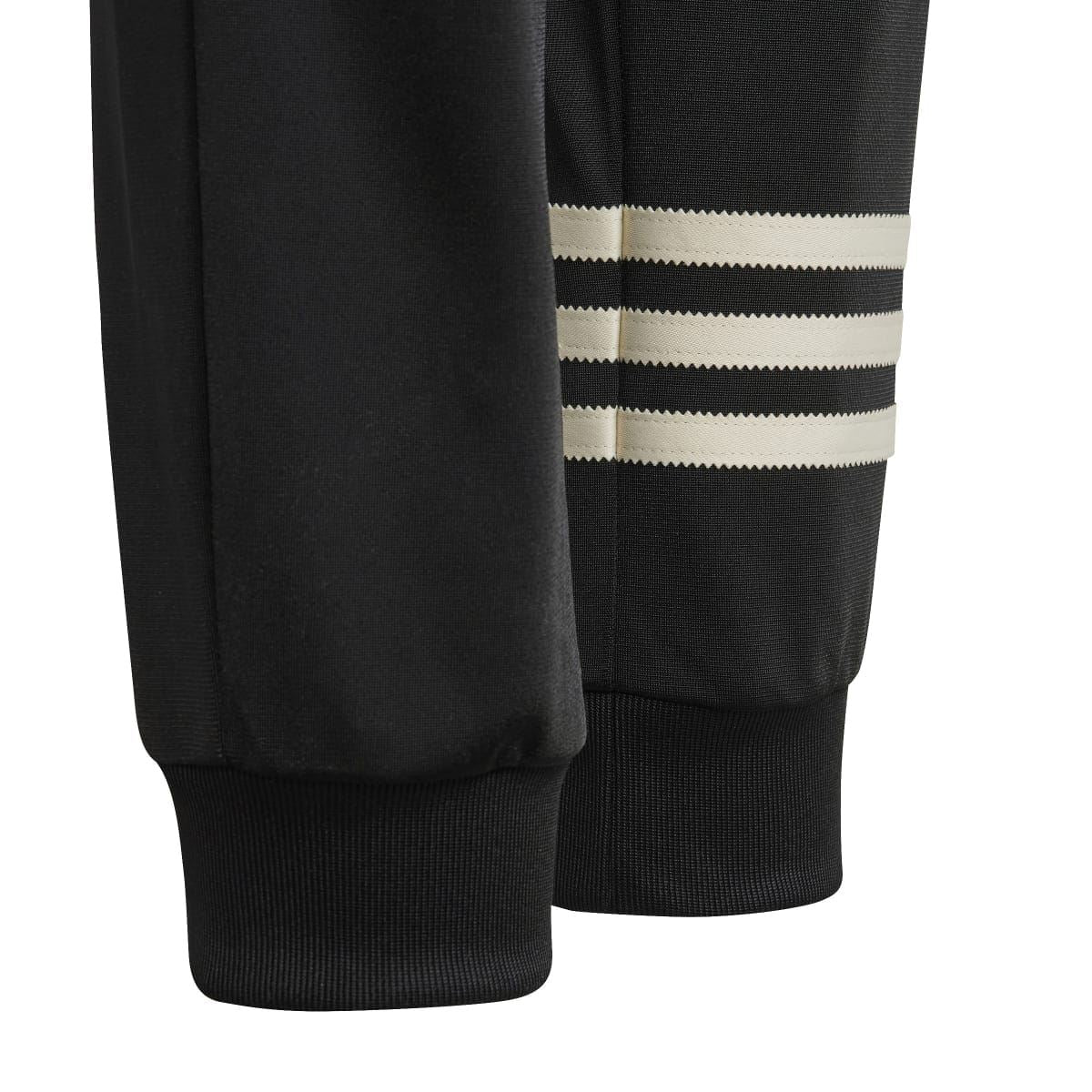 Black track pants cuff with ribbed hem and adidas-style striped band detail