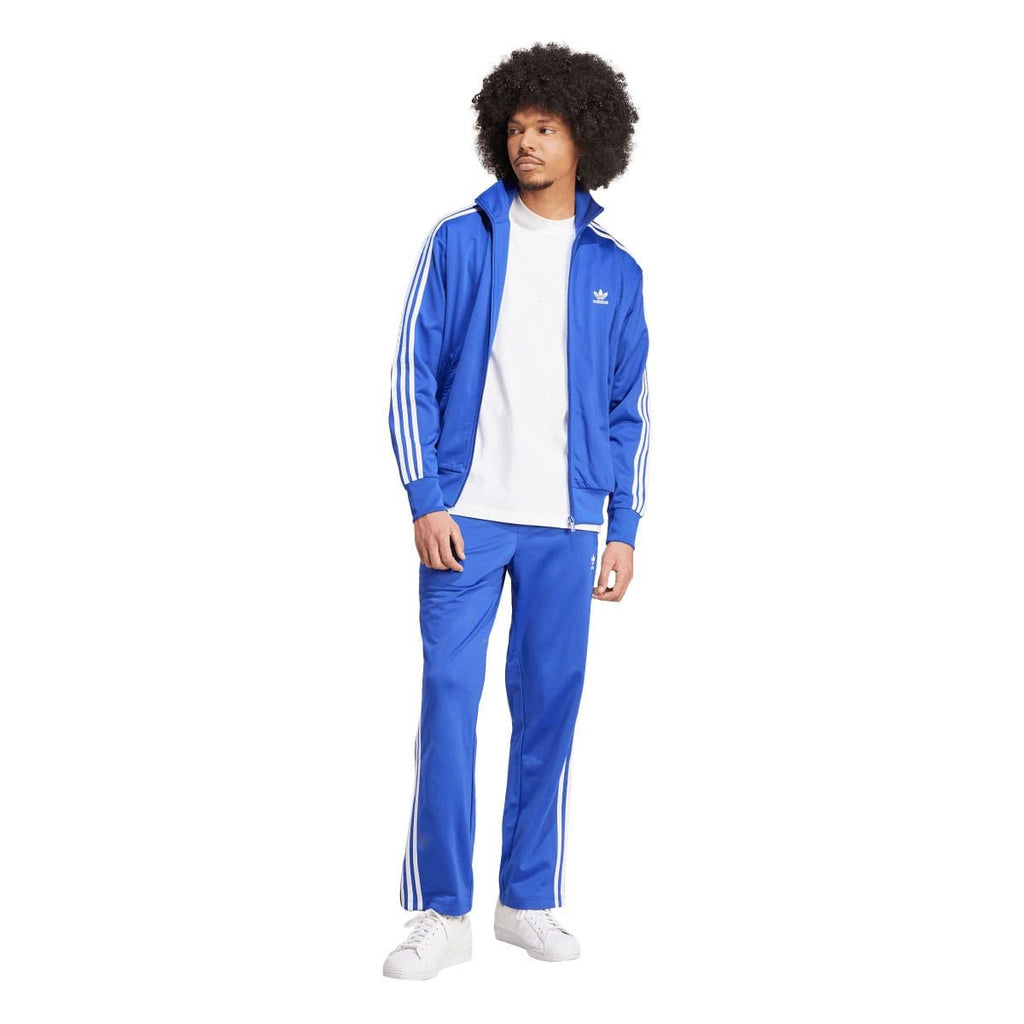 Blue adidas track pants with white side stripes and elastic waist
