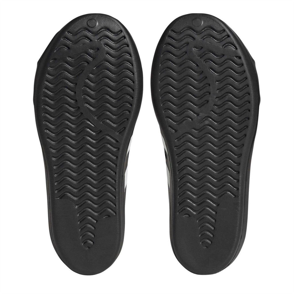 Black sneaker outsoles with wavy tread patterns and adidas logo on each sole