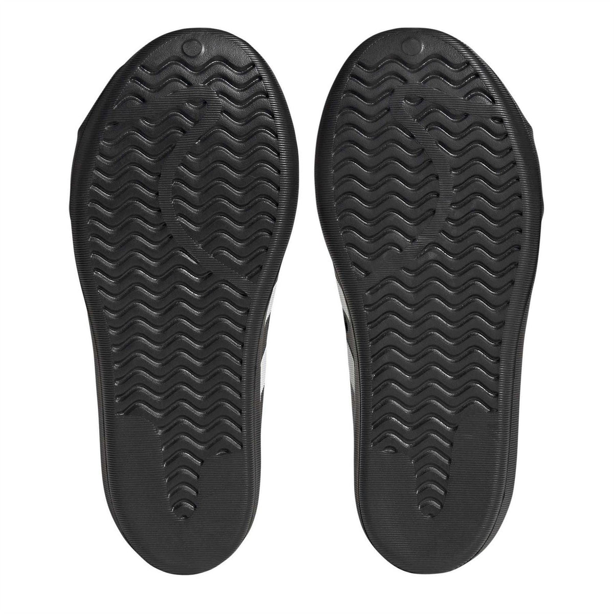Black sneaker outsoles with wavy tread patterns and adidas logo on each sole