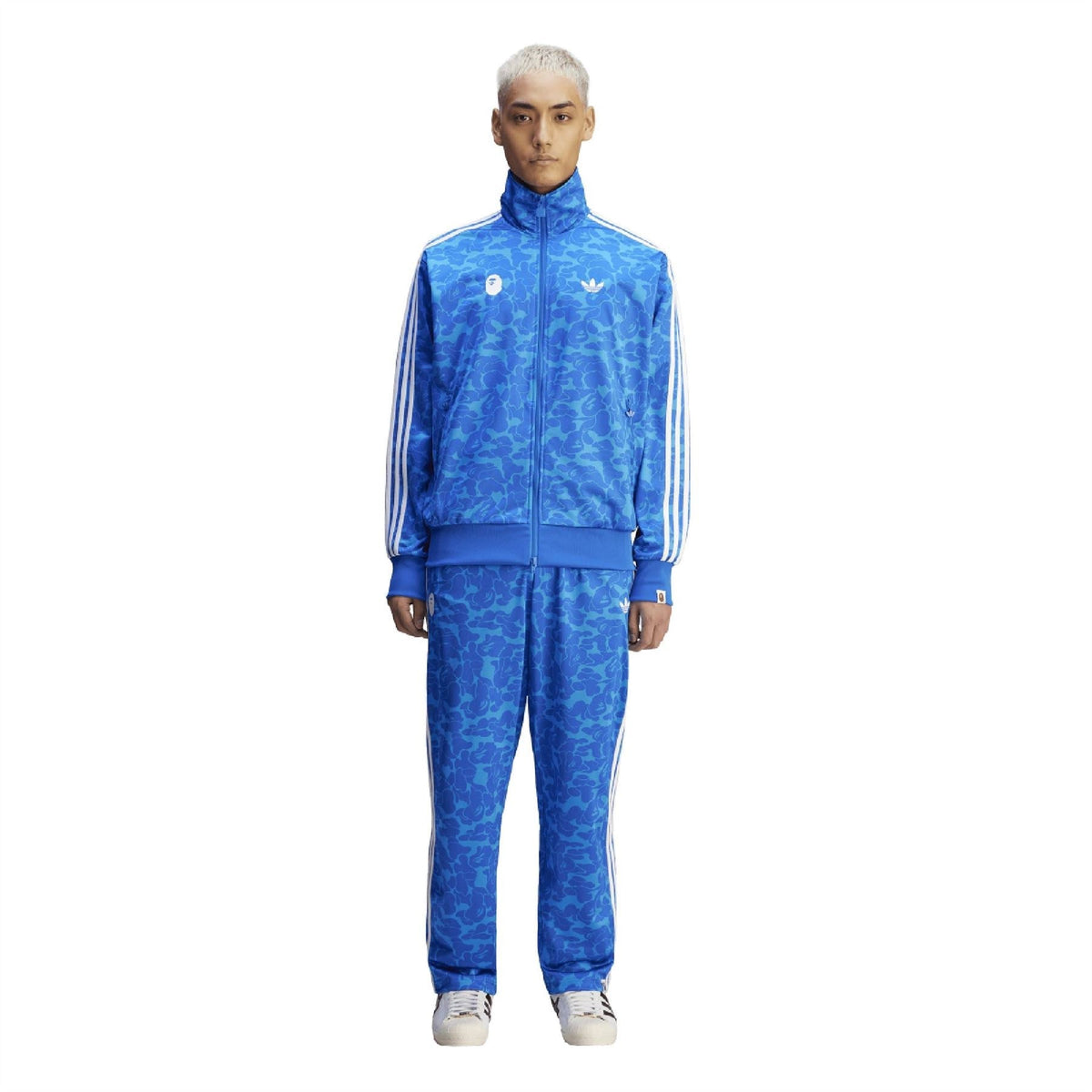 Blue camouflage adidas track pants with white side stripes and elastic cuffs