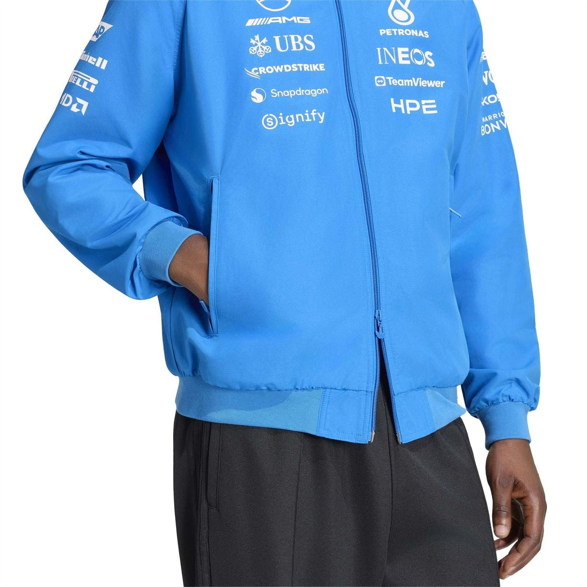 Blue zip-up jacket with ribbed cuffs and printed sponsor logos on chest and sleeves.