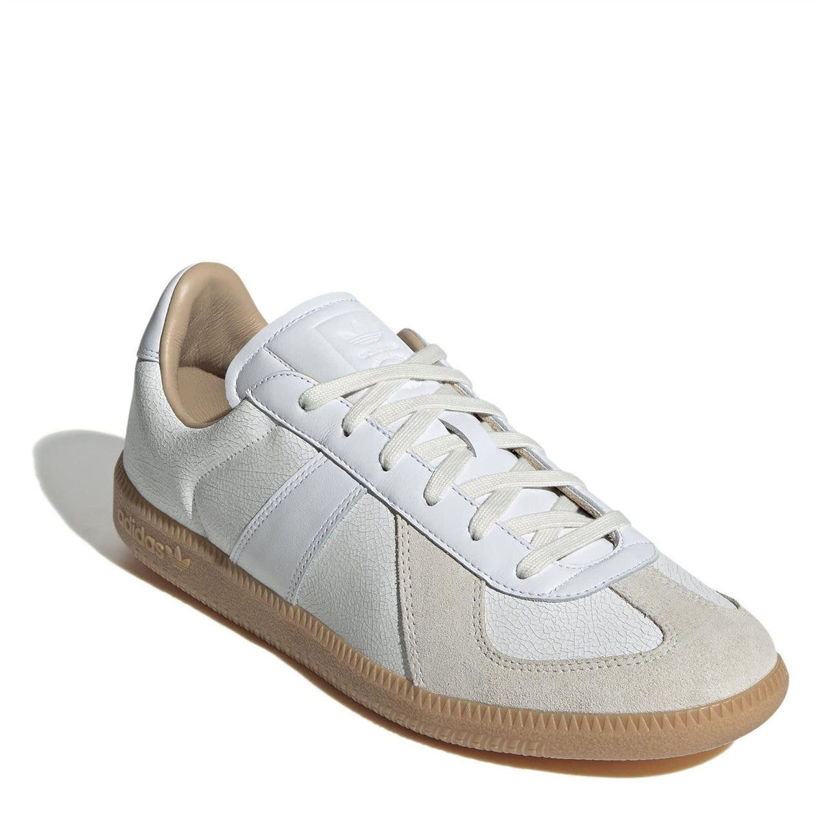 Low-top adidas sneakers with white upper, beige trim, cream laces, and gum cupsole