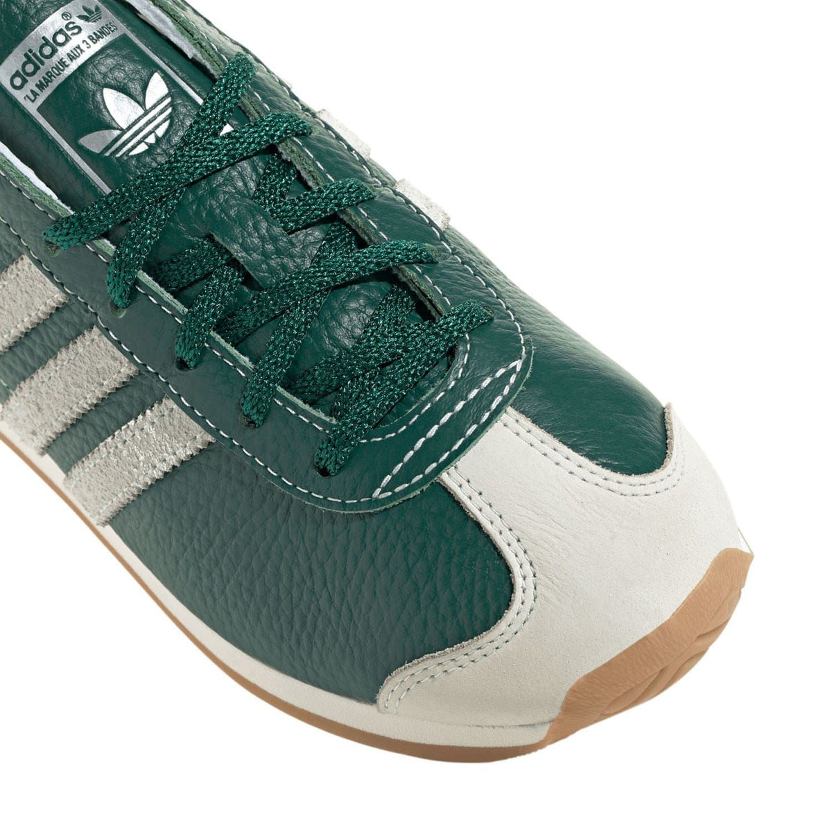 Close-up of green and white adidas Originals trainers with stitched stripes and laces