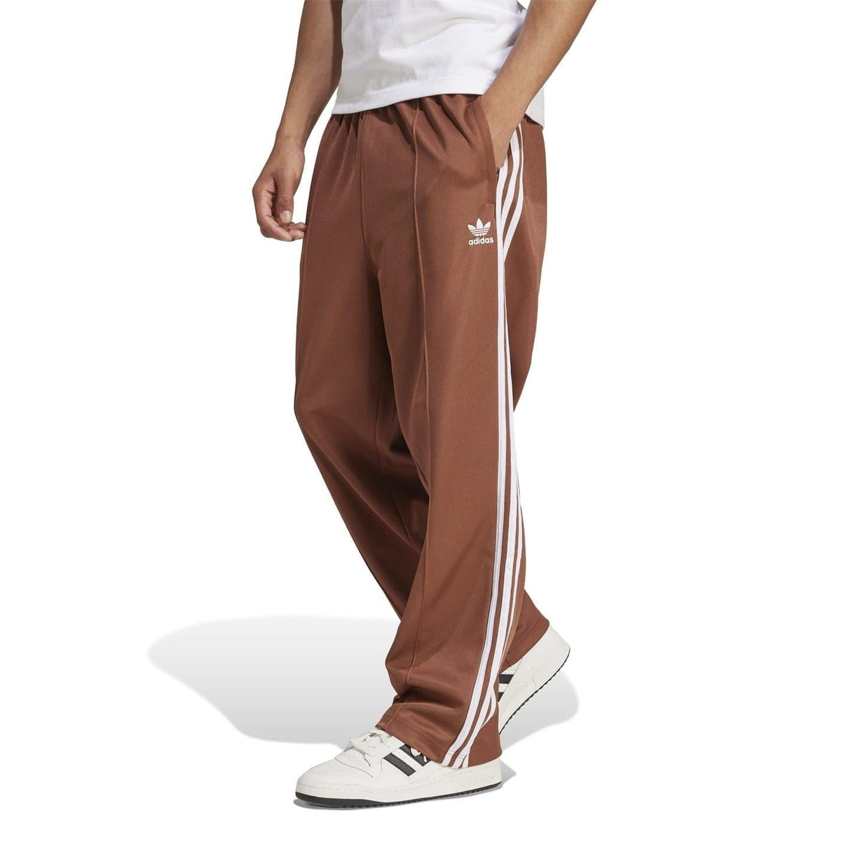 Brown track pants with elastic waist, loose fit, white triple side stripes and adidas logo