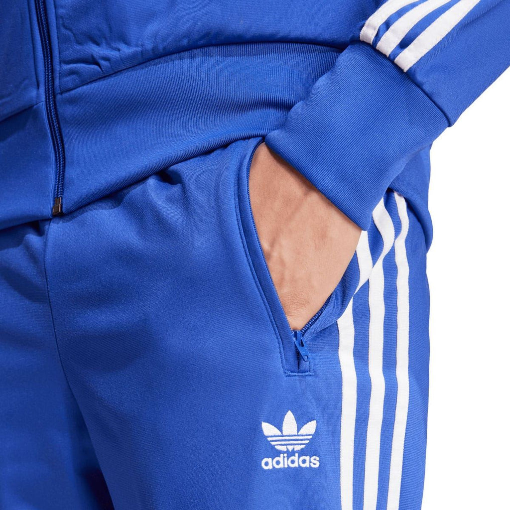 Blue track pants with adidas logo, front pocket, and elastic waistband