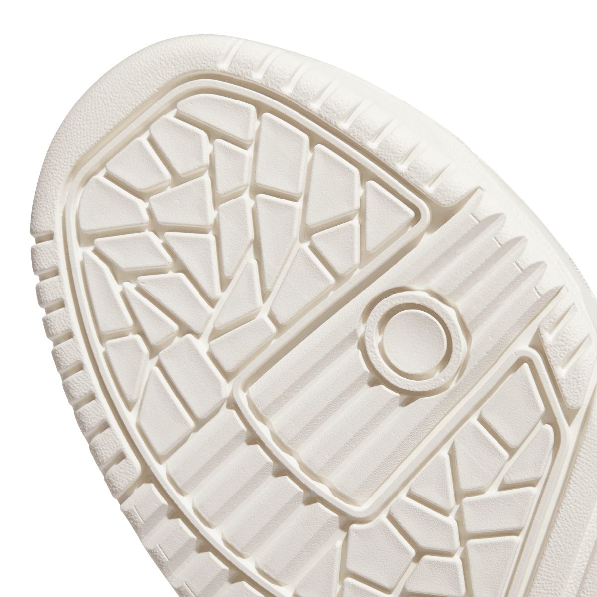 White rubber outsole close-up with geometric tread and raised circular mark.