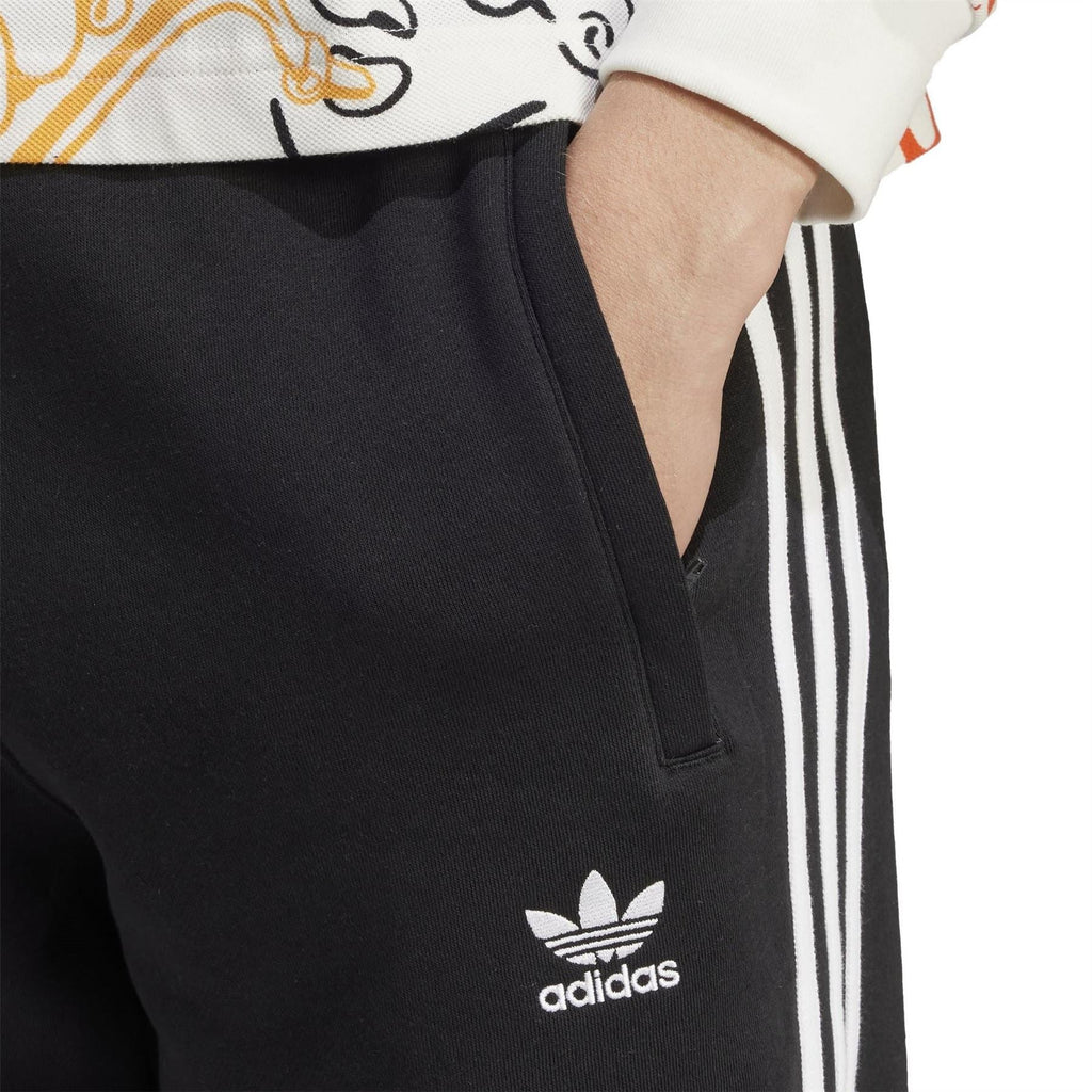 Black slim joggers with white side stripes and adidas trefoil logo at hip