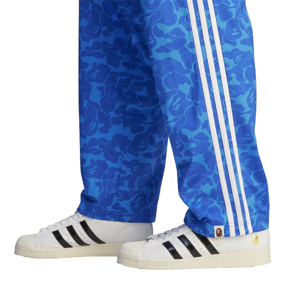 Blue camo track pants with white triple stripes at the hem, styled with sneakers