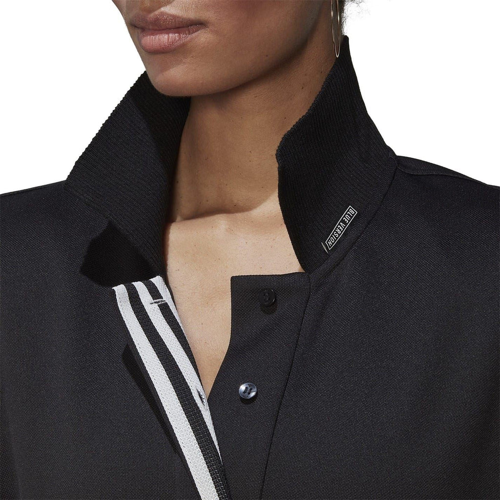 Black polo dress collar close-up with button placket and adidas logo patch.
