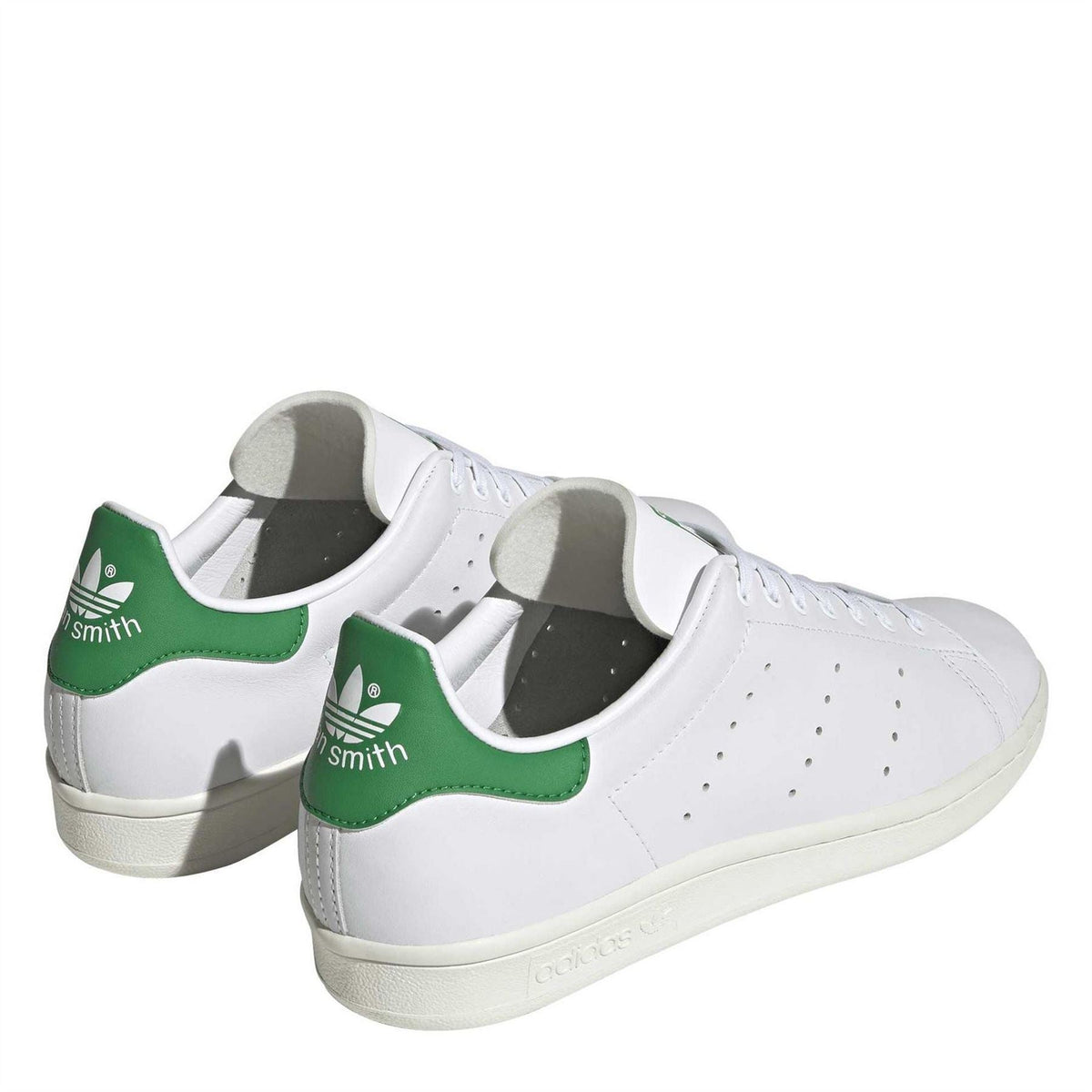 White low-top sneakers with green heel tabs, lace-up front, and cream sole