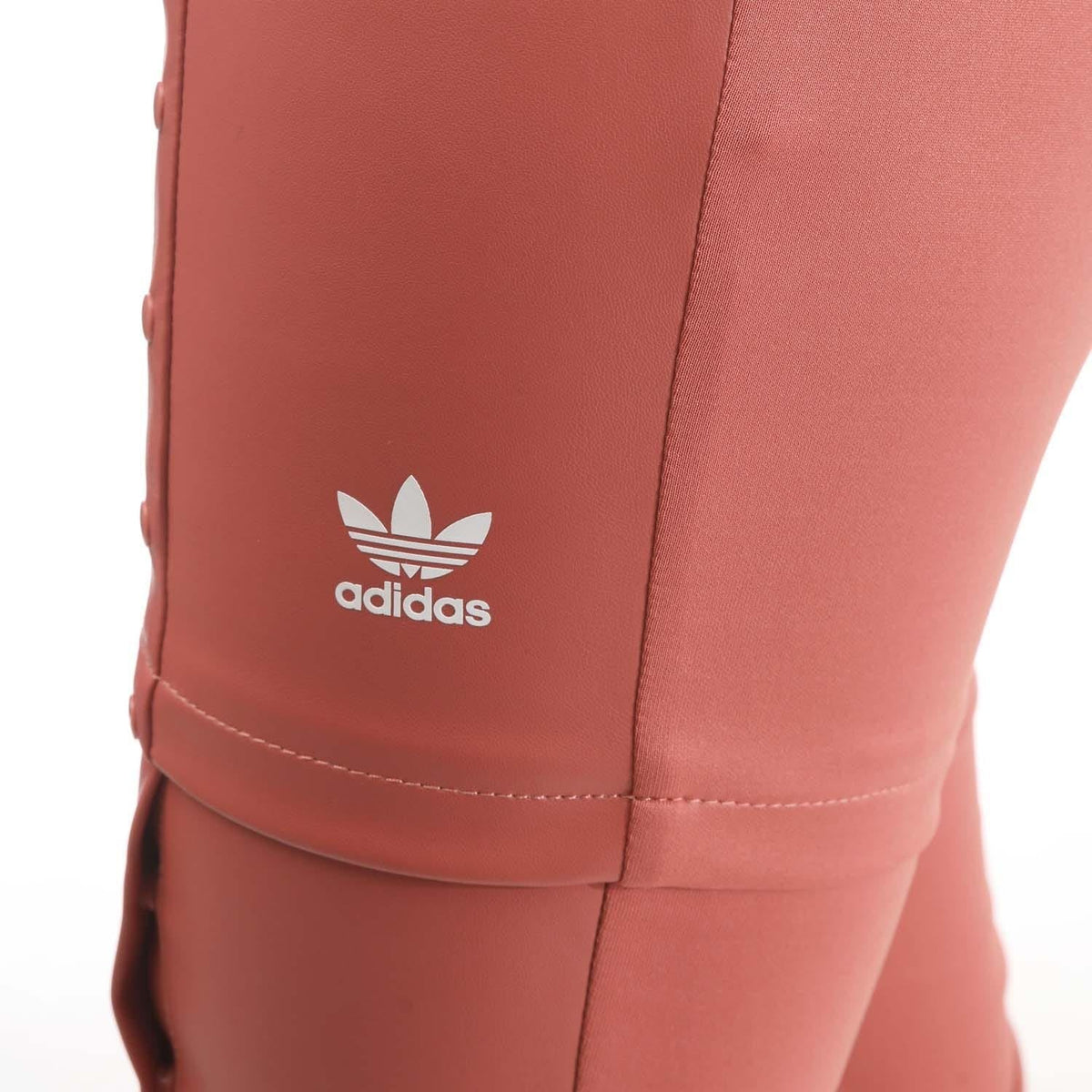 Adidas trefoil logo on red snap-button pants leg with visible stitching