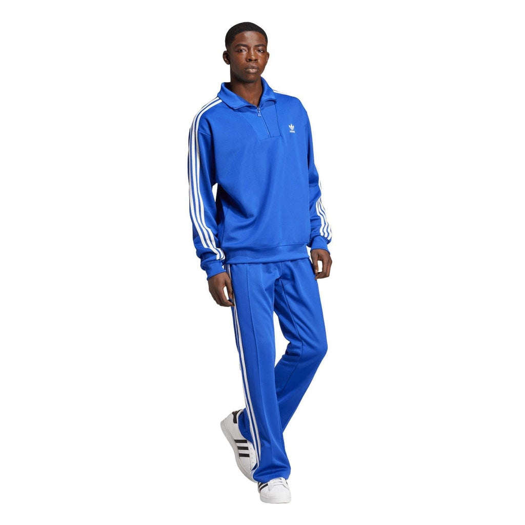 Blue adidas track top with funnel neck and white sleeve stripes, worn with matching joggers.