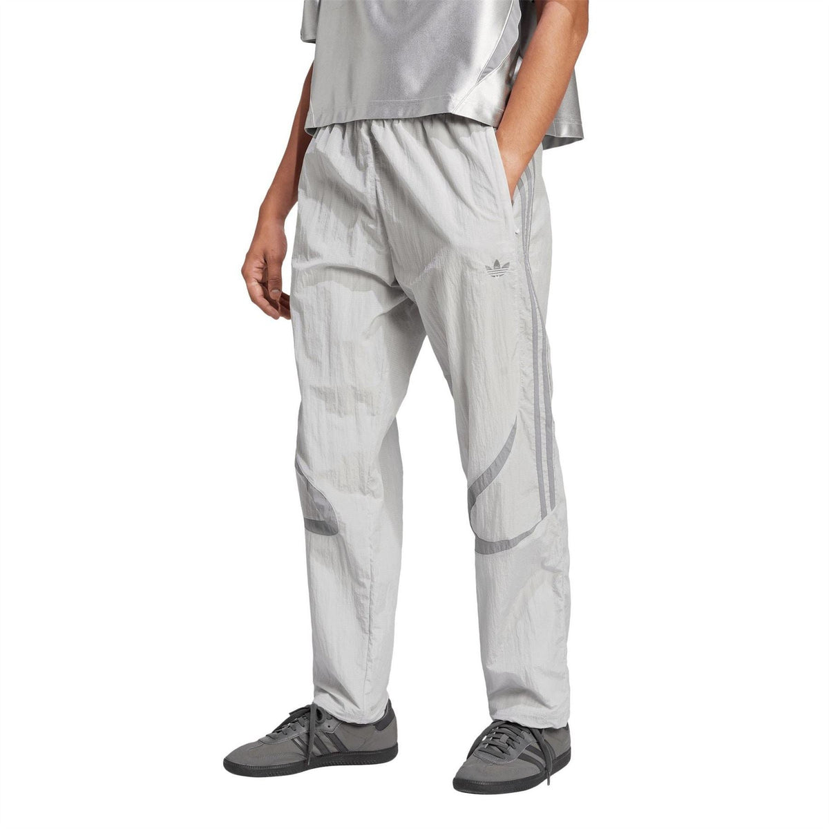 Light grey track pants with elastic cuffs and adidas logo on the leg, with sneakers