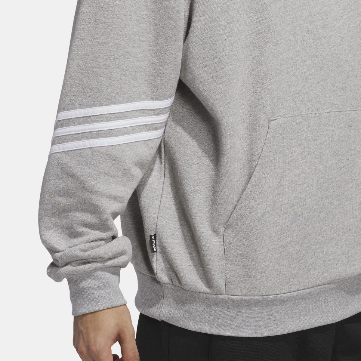 Grey hoodie close-up of striped sleeve cuff and kangaroo pocket seam.