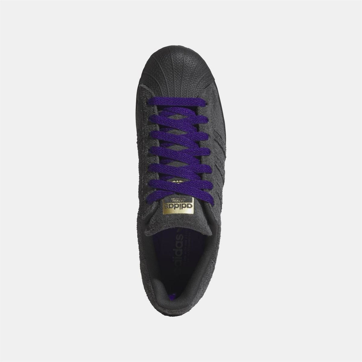 Black sneaker with purple laces, lace eyelets, and adidas logo on tongue