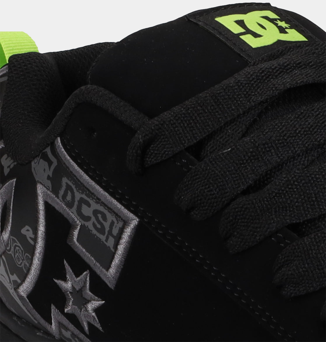 Close-up of black low-top sneakers with neon green logo patch and lace stitching