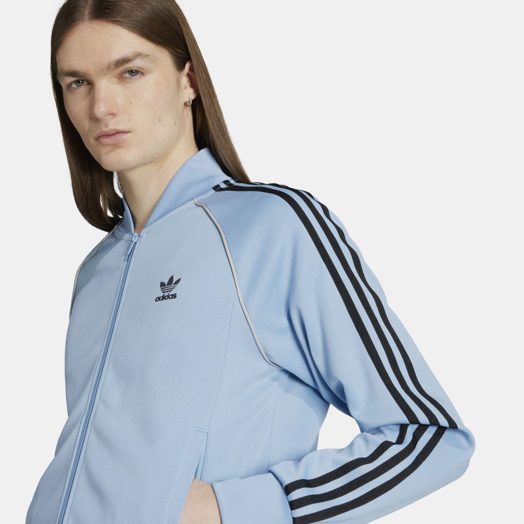 adidas Originals Adicolor Classic SST track jacket in navy with white stripes, featuring a zip-up front and ribbed cuffs.