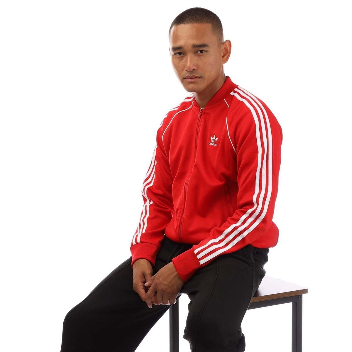 Red adidas track jacket with white triple sleeve stripes and full zip front.