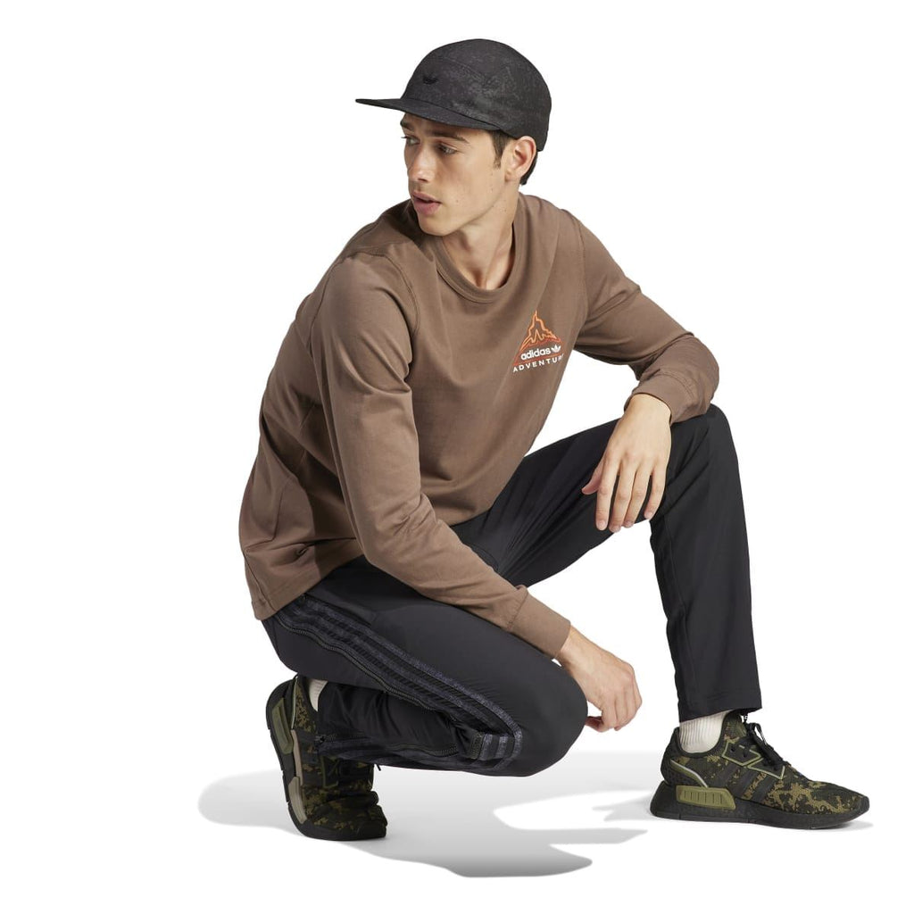 adidas Originals brown long-sleeve T-shirt worn with cap; crew neck and adventure logo