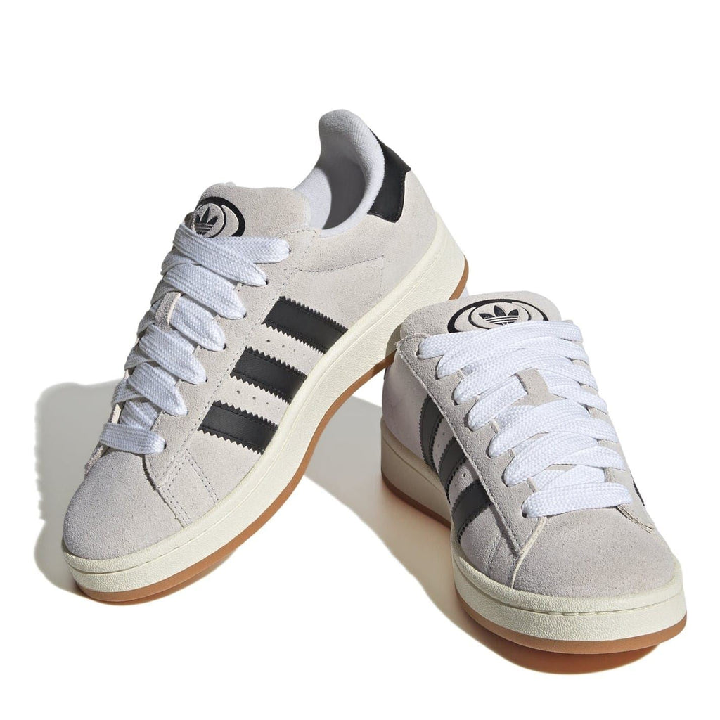 Pair of light gray adidas low top sneakers with white laces, black stripes, and gum sole