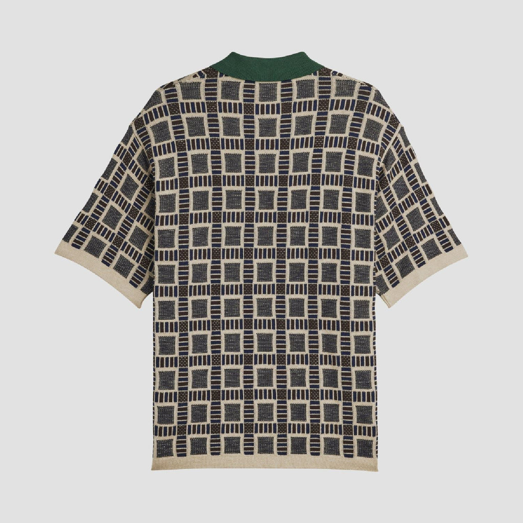 Sand polo shirt with green collar and short sleeves; repeating navy-and-cream geometric pattern.