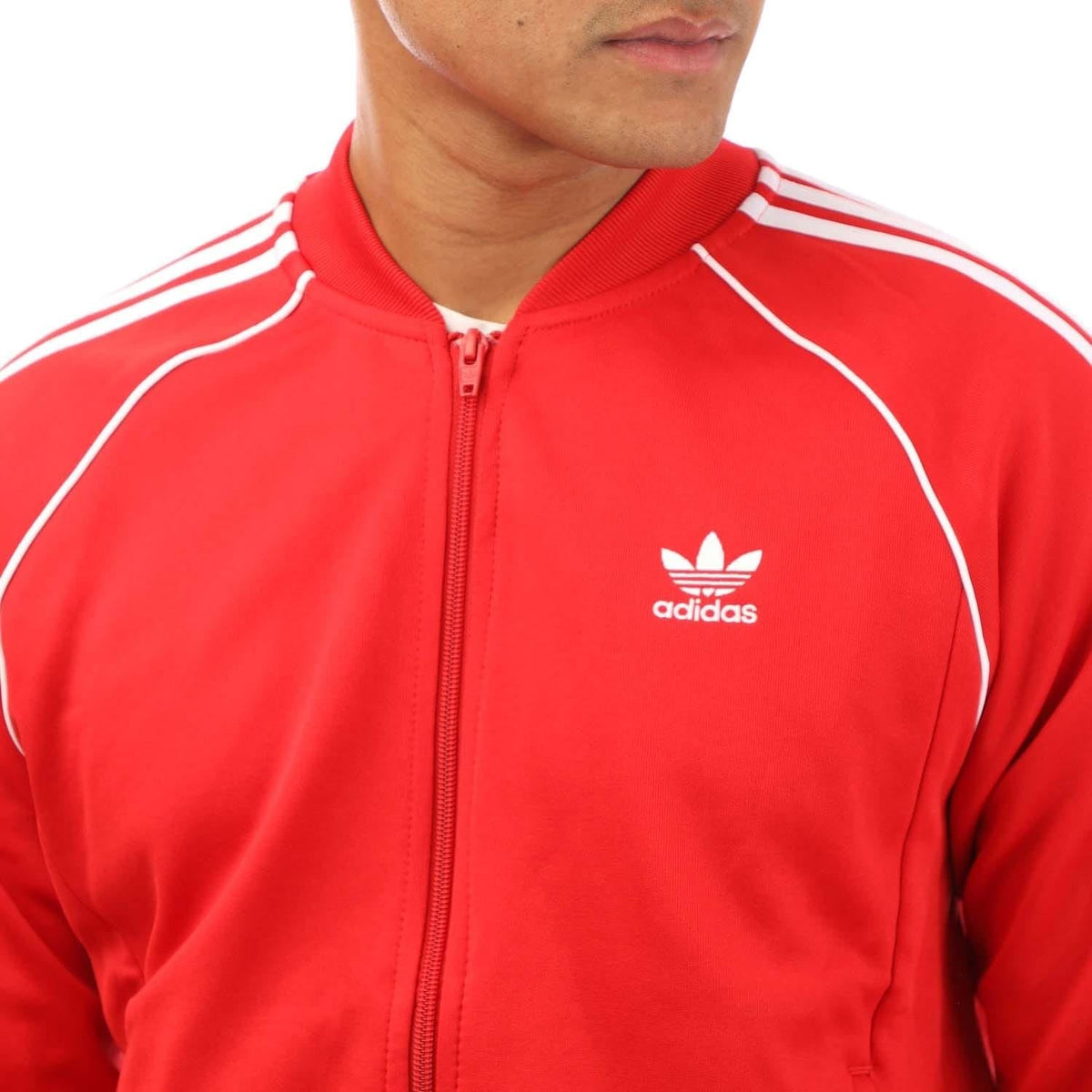 Red track jacket close-up with adidas logo, full-zip front and white piping stripes