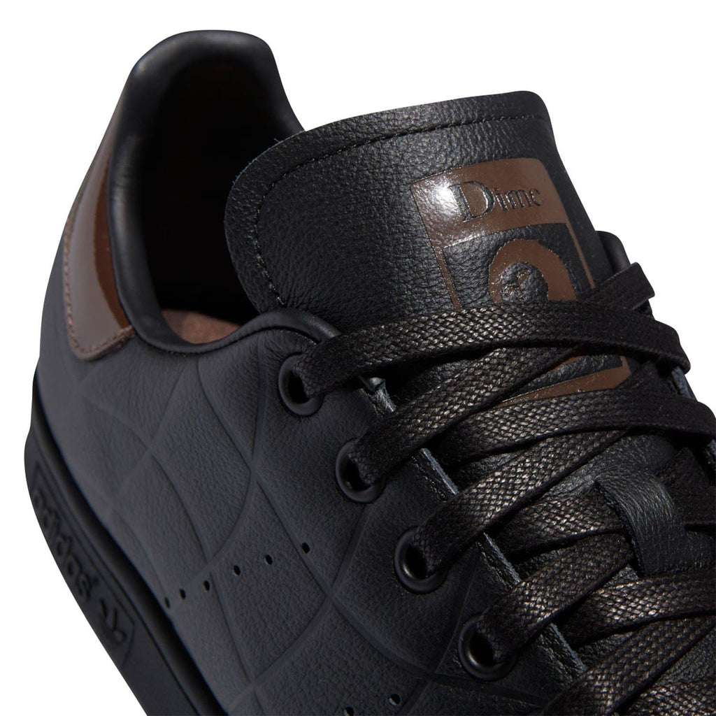 Black leather lace-up trainer close-up with Dime badge and brown collar stitching