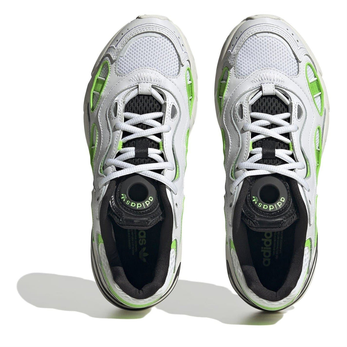 Front view of white sneakers with neon green trim, black tongue, and lace-up eyelets
