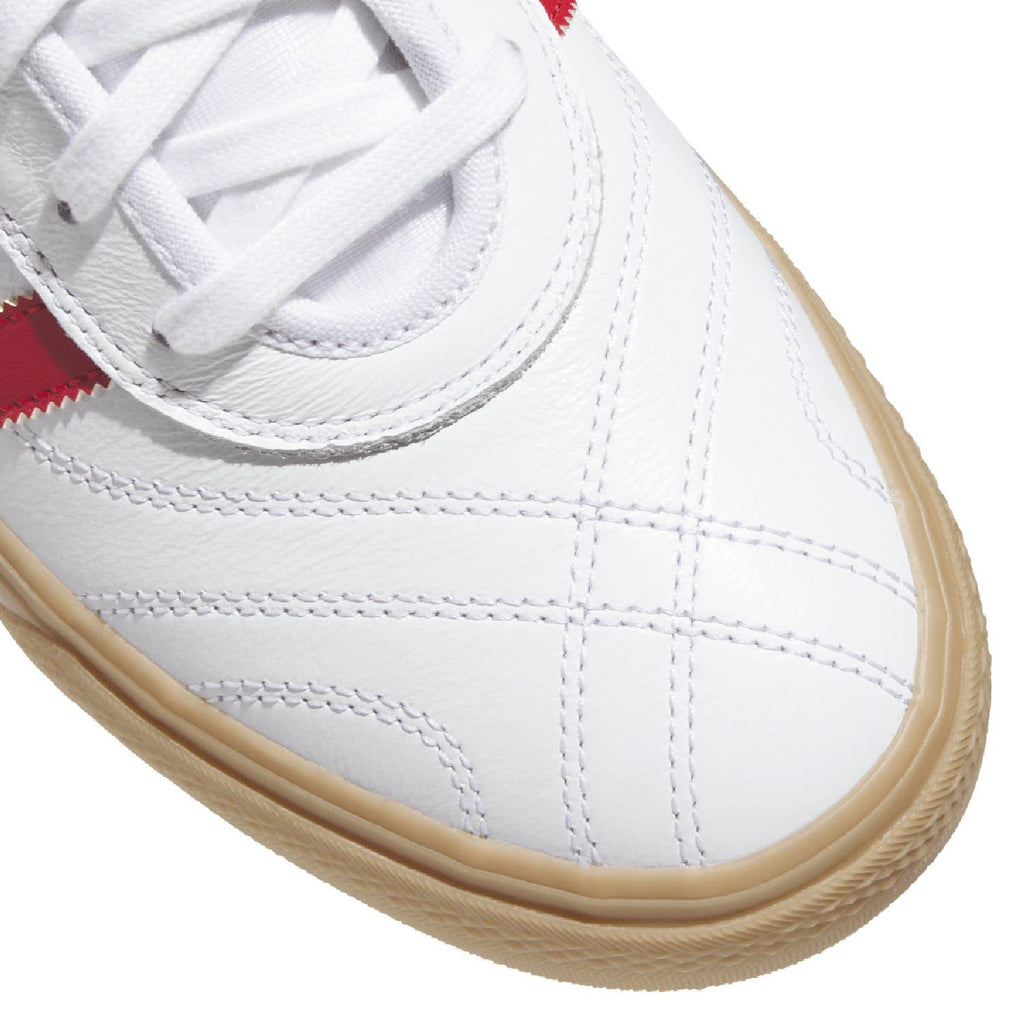 Close-up of white adidas Adiease trainers showing laces and gum-brown sidewall