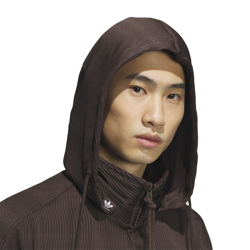 Brown hooded jacket close-up with adidas Trefoil at neckline and textured ribbed surface