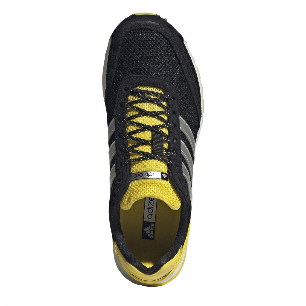 Black low-top sneakers with yellow lace overlay and adidas logo on tongue