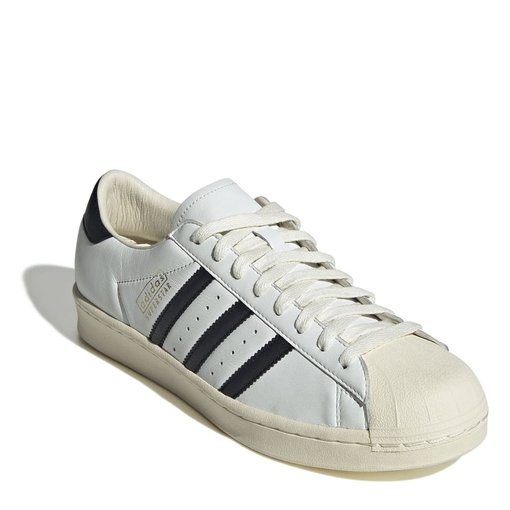 White low-top sneakers with black side stripes, lace-up, chunky beige sole