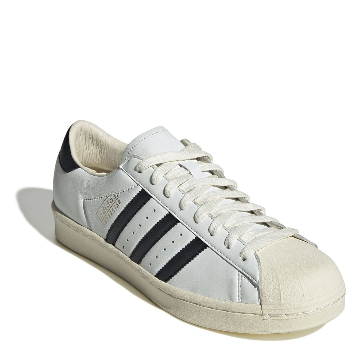 White low-top sneakers with black side stripes, lace-up, chunky beige sole