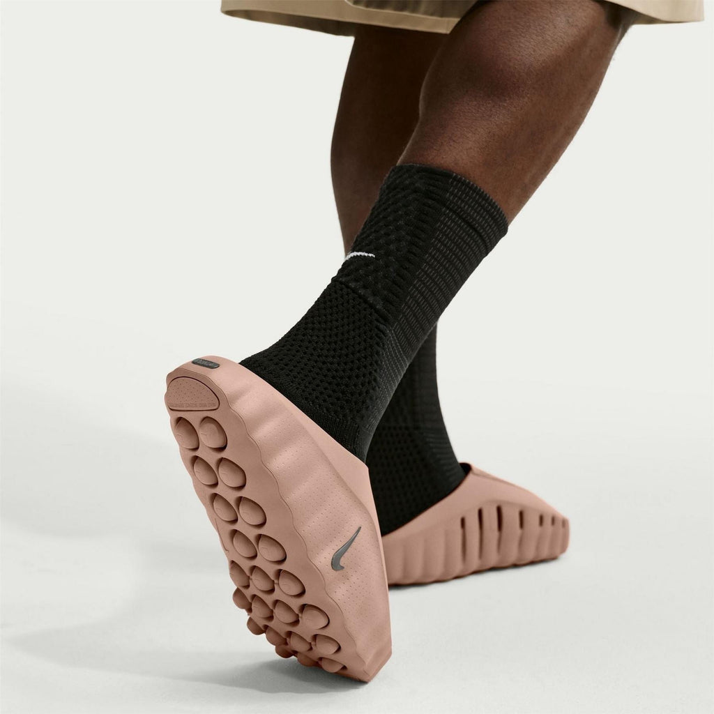 Blush pink Nike slide sandals with black ankle socks and textured footbed