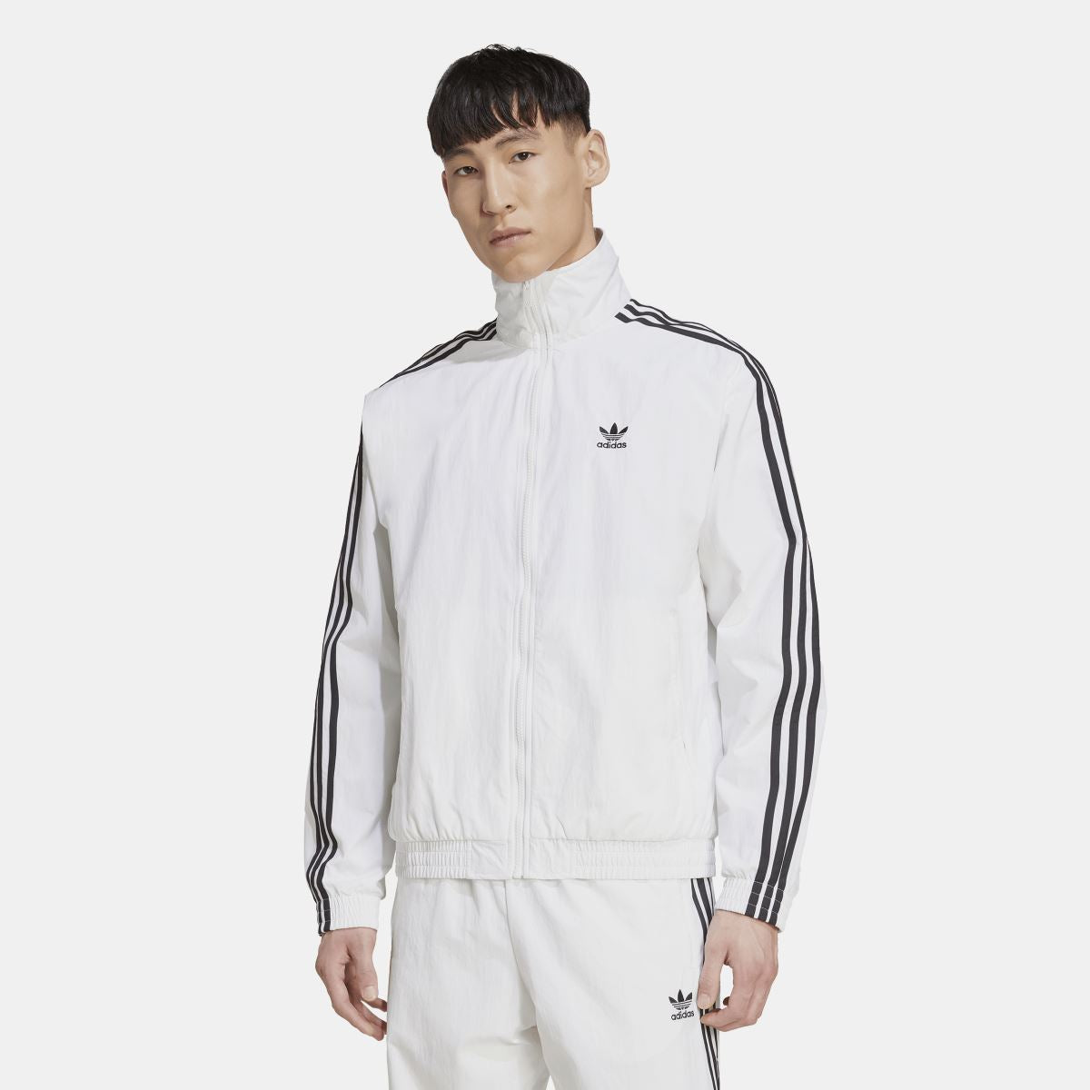 White adidas track top with stand collar, front zip, and black triple-stripe sleeve details
