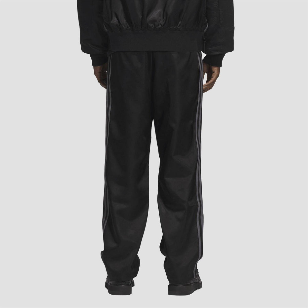 Black track pants with vertical side stripe detailing and tapered ankle cuffs