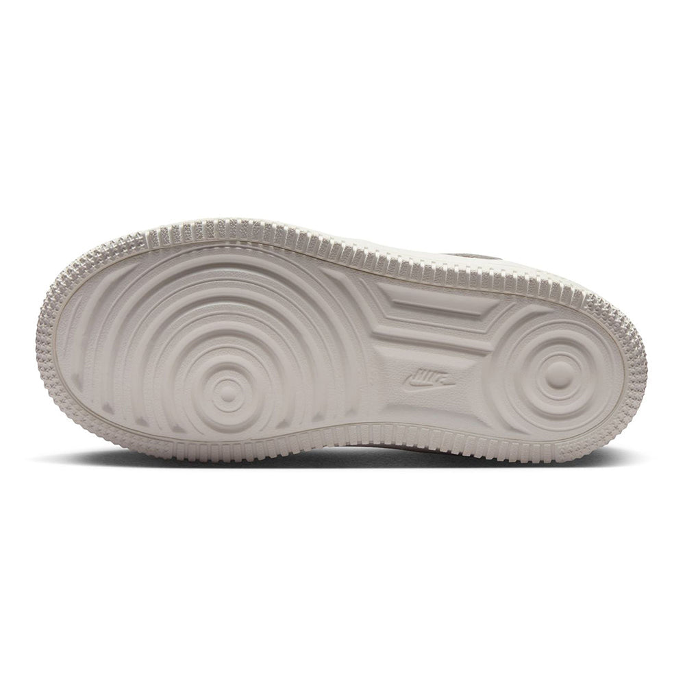 Kids sneaker outsole with textured tread and Nike mark on white rubber sole