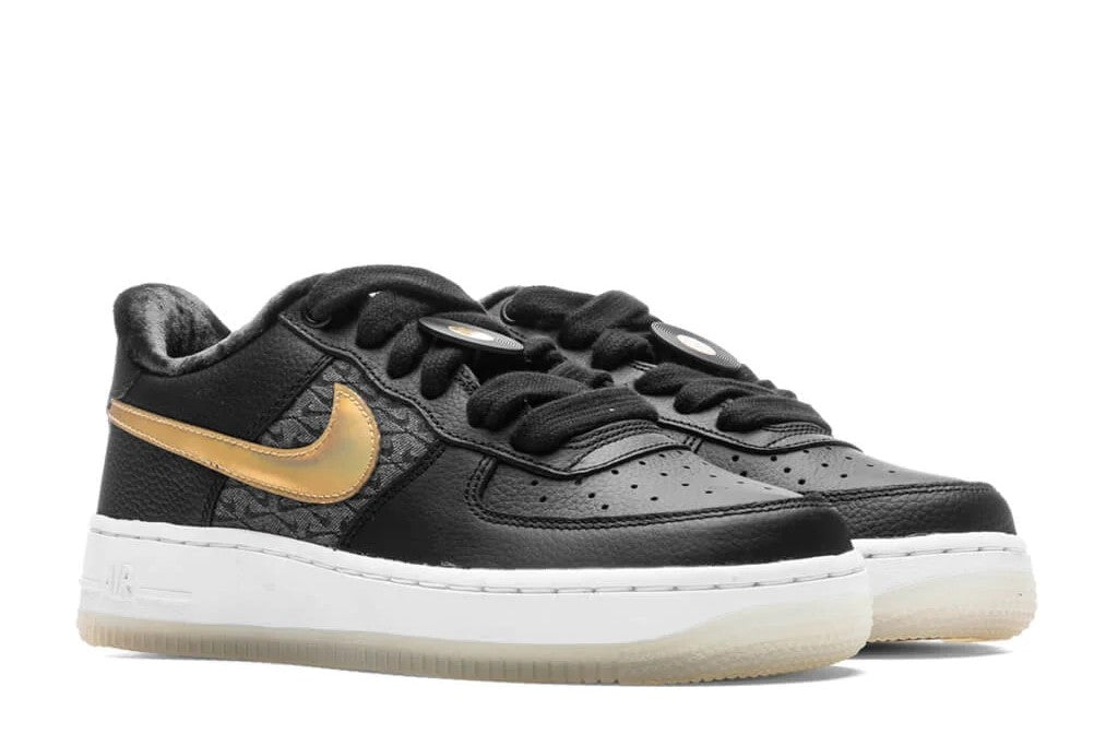 Kids black low-top sneakers with gold swoosh, white midsole, and black lace-up