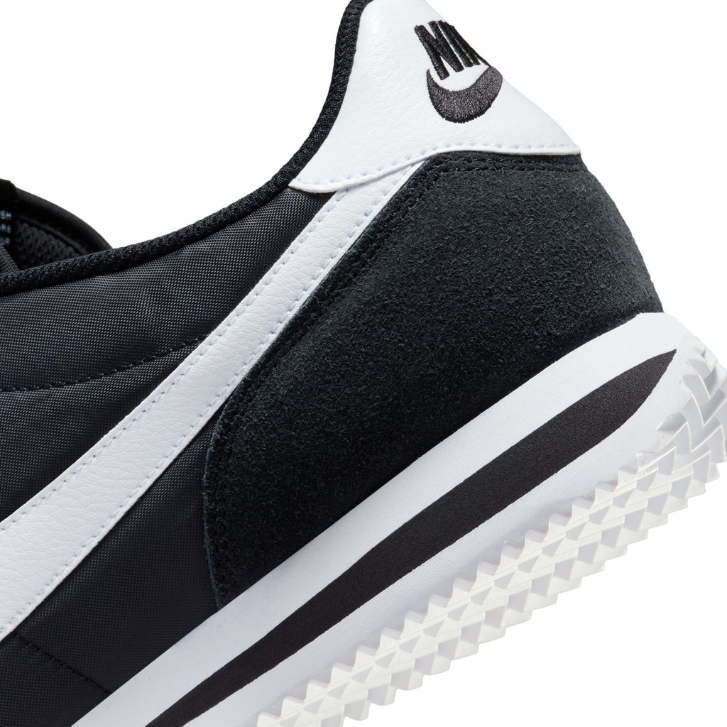 Nike Cortez TXT sneaker close-up, black suede and mesh with white stripe, grippy sole